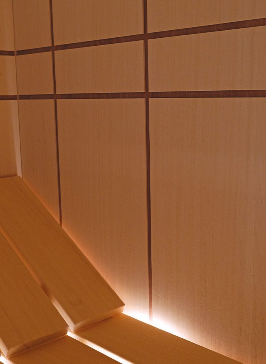 Sauna italiana con revestimiento en tonos cobre y líneas verticales iluminadas