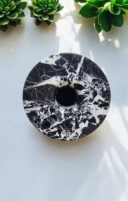 Pieza circular de mármol negro veteado con abertura central